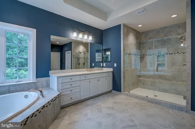 a bathroom with a tub a double vanity sink a window and a mirror