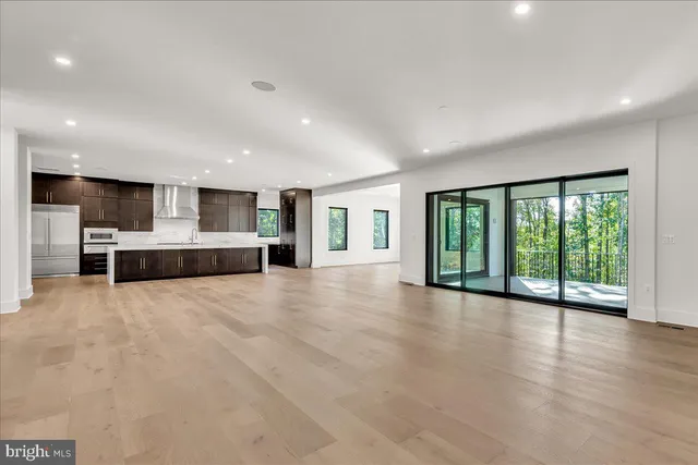 a view of an empty room with wooden floor and a kitchen