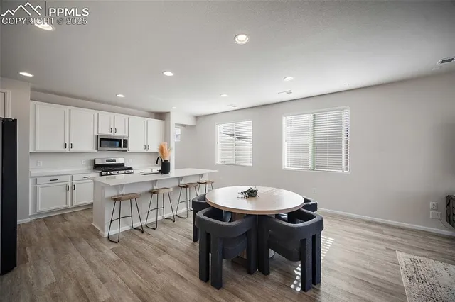 a kitchen with a dining table chairs and refrigerator