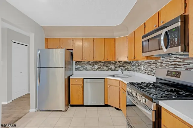 a kitchen with stainless steel appliances granite countertop a refrigerator a stove and a sink