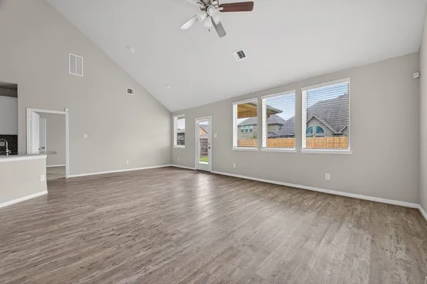 a view of an empty room with window and wooden floor