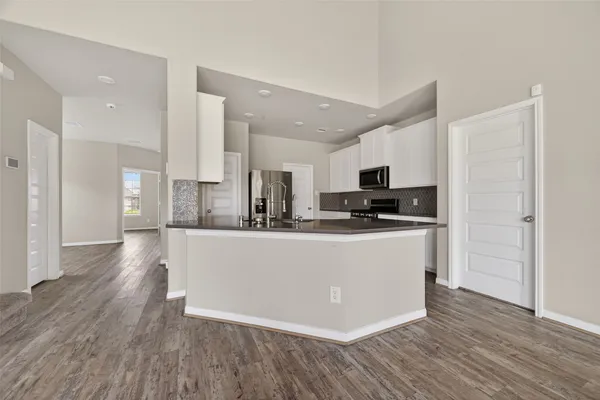 a view of kitchen with stainless steel appliances granite countertop a stove top oven a refrigerator a sink and dishwasher with wooden floor