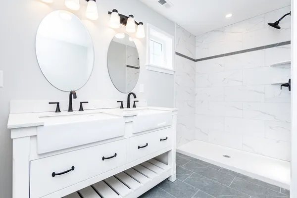 a bathroom with a double vanity sink mirror and shower