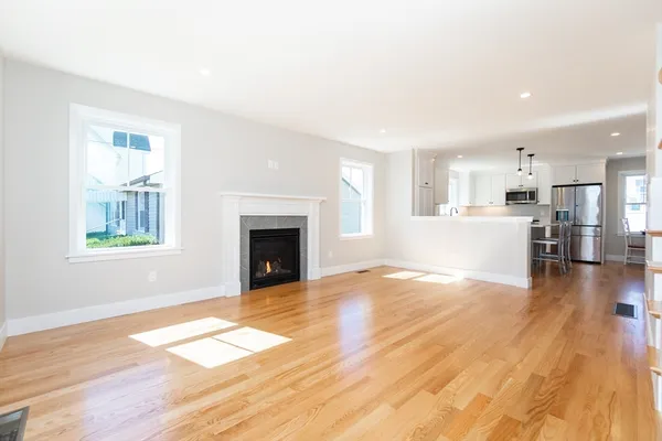 a view of a livingroom with wooden floor and a kitchen