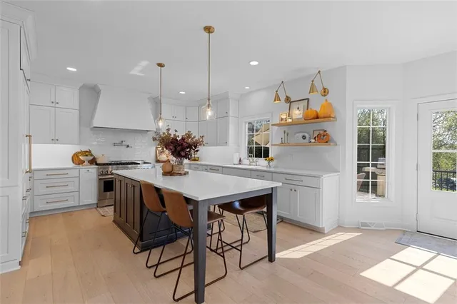 a kitchen with stainless steel appliances kitchen island a table chairs in it and wooden floors