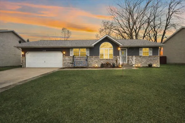 a front view of a house with a garden and trees