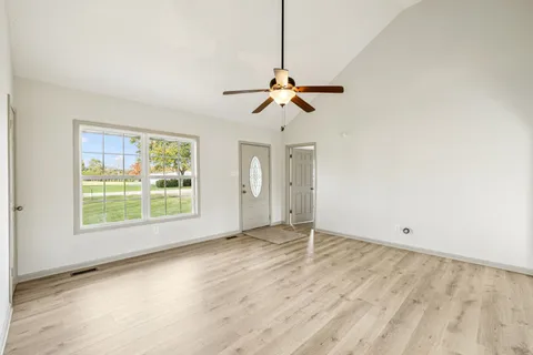 a view of an empty room with window and wooden floor