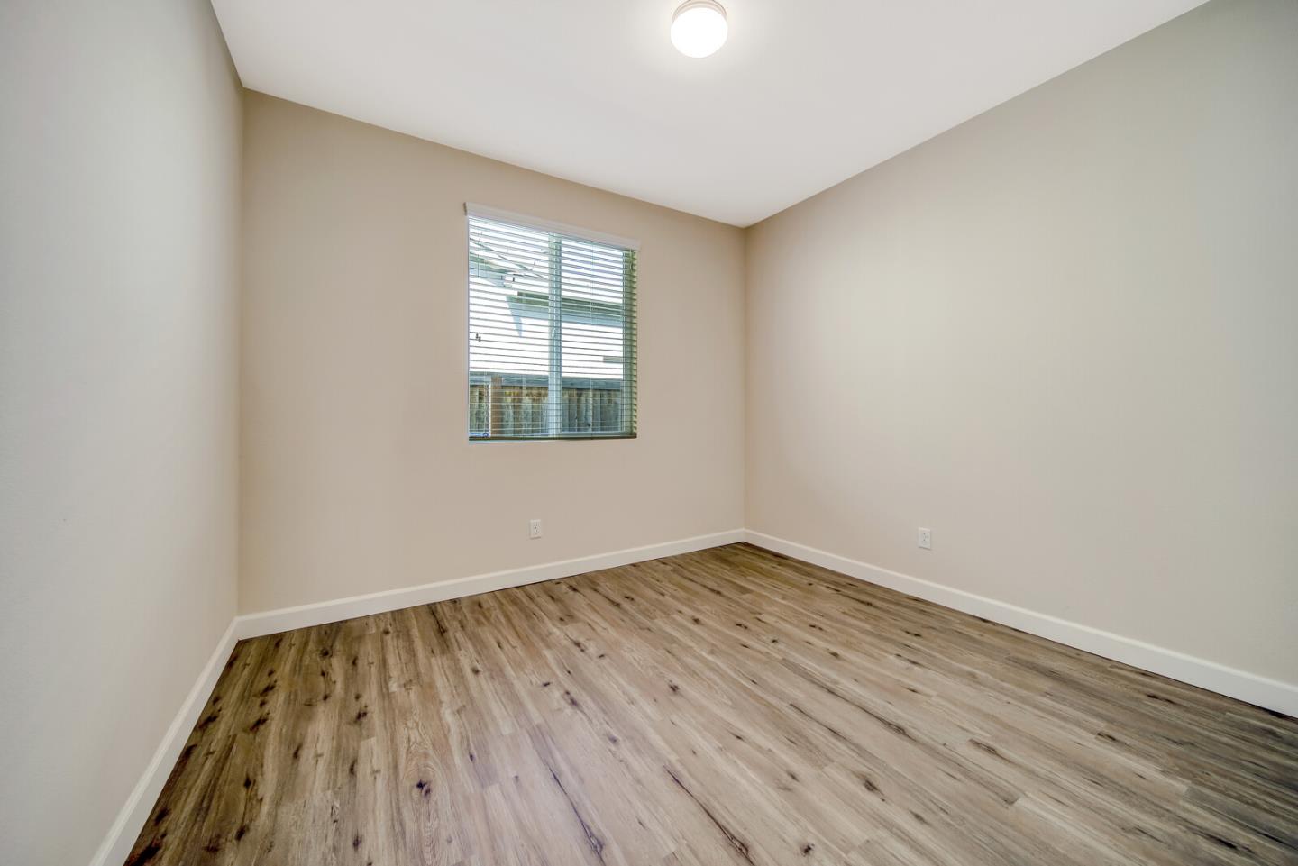 1479 Orgullo Lane Manteca, CA 95337 - Photo 21 of 39 an empty room with wooden floor and windows