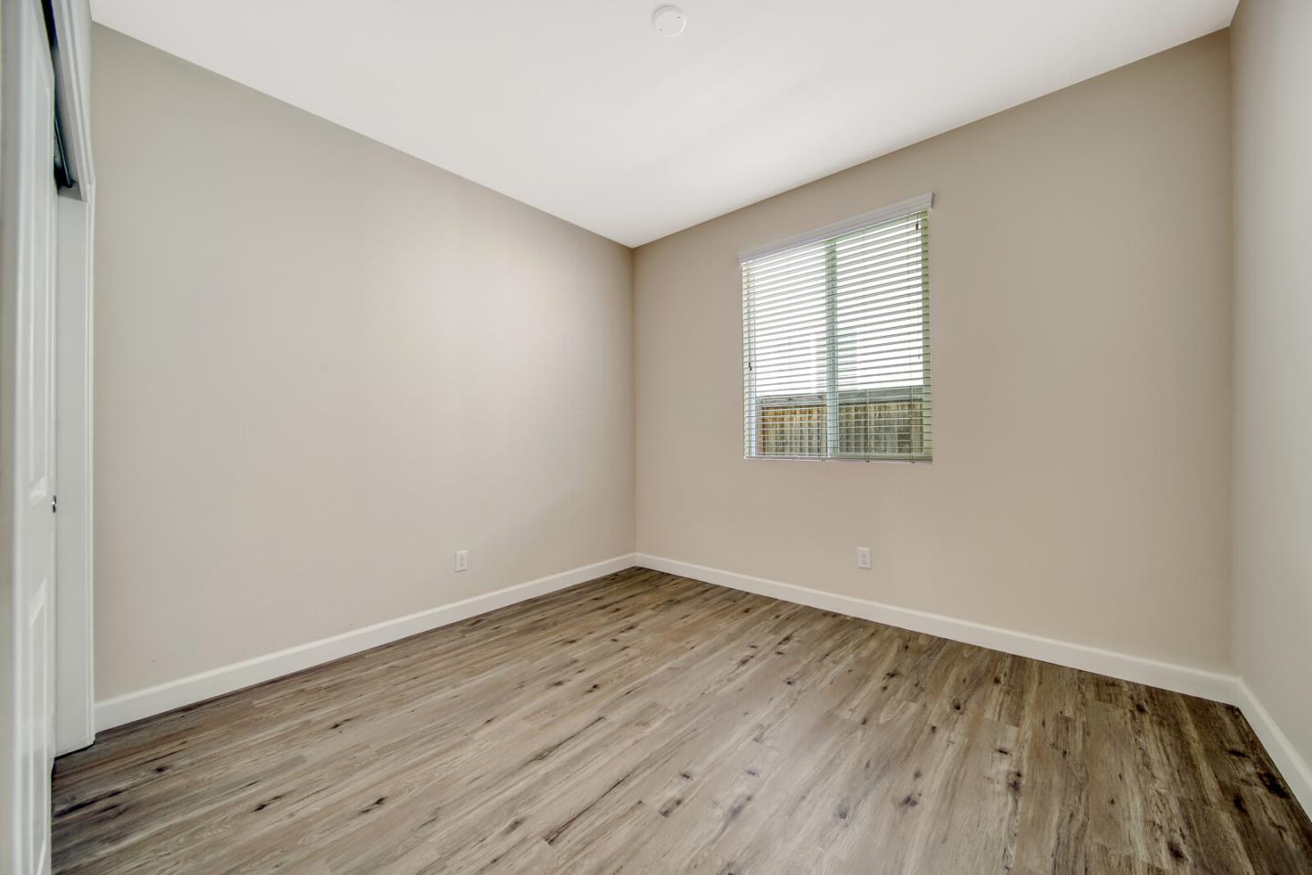 1479 Orgullo Lane Manteca, CA 95337 - Photo 24 of 39 an empty room with wooden floor and windows