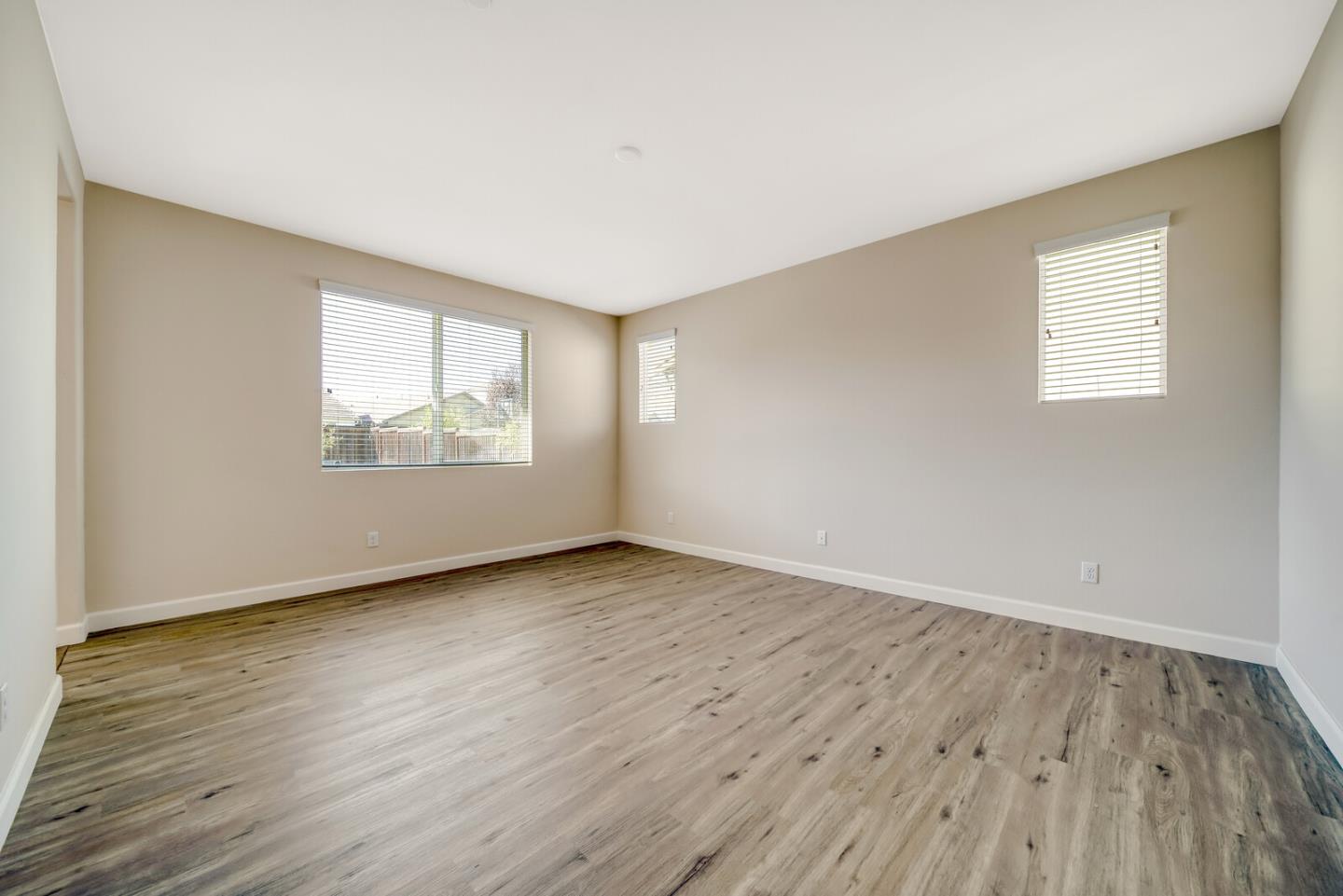 1479 Orgullo Lane Manteca, CA 95337 - Photo 27 of 39 an empty room with wooden floor and windows