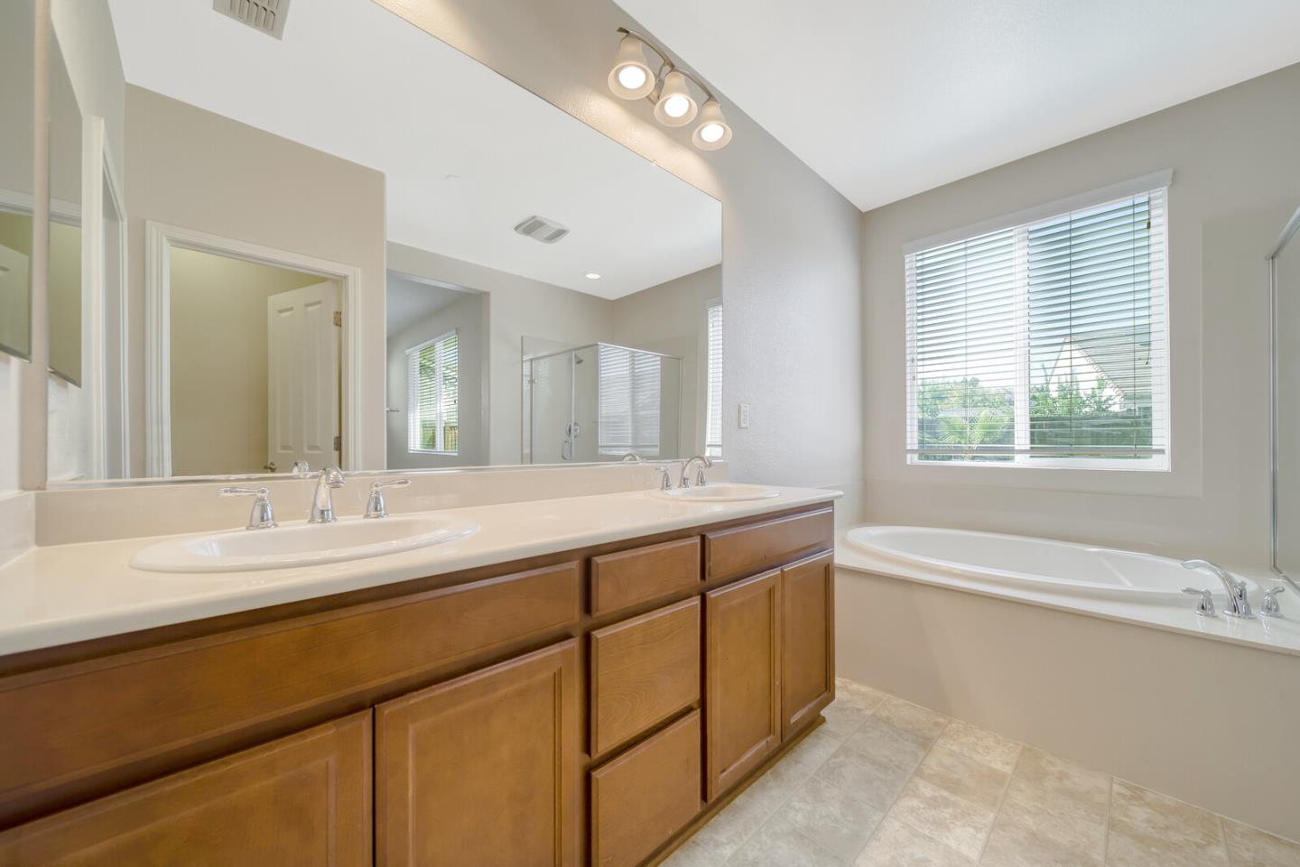1479 Orgullo Lane Manteca, CA 95337 - Photo 33 of 39 a bathroom with a granite countertop sink mirror and a bathtub
