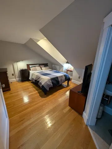 a bedroom with a bed and a flat tv screen on a dresser