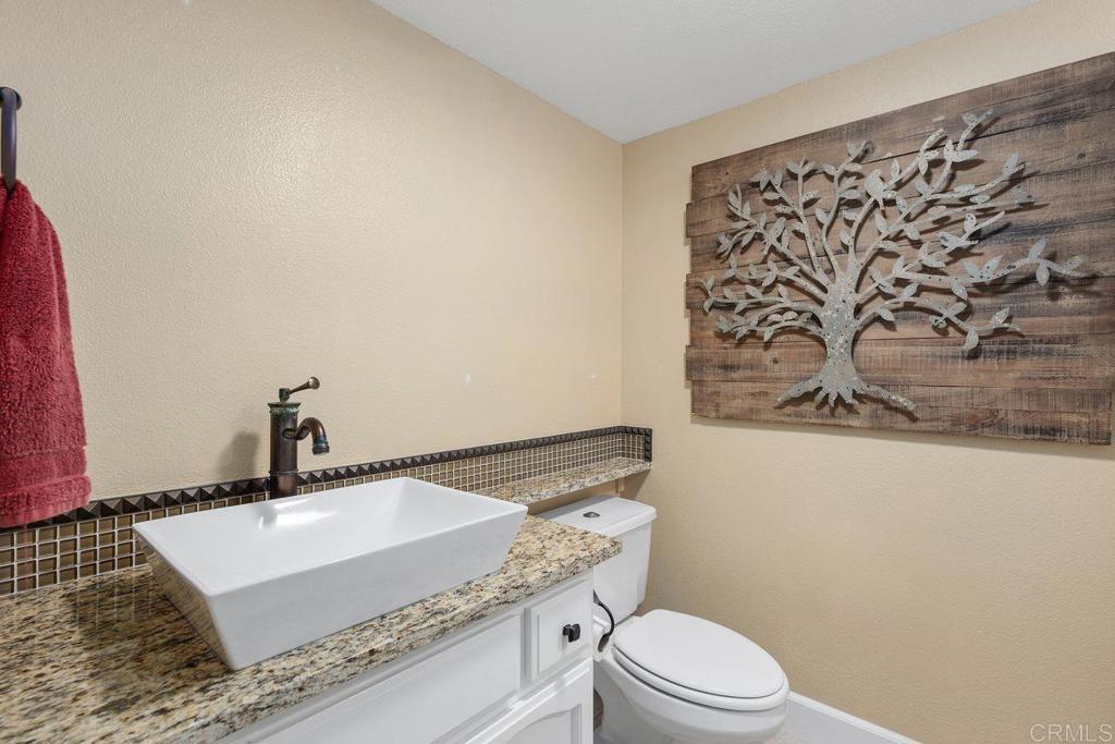 7325 Lantana Terrace Carlsbad, CA 92011 - Photo 14 of 36 a bathroom with a granite countertop sink a mirror and a toilet