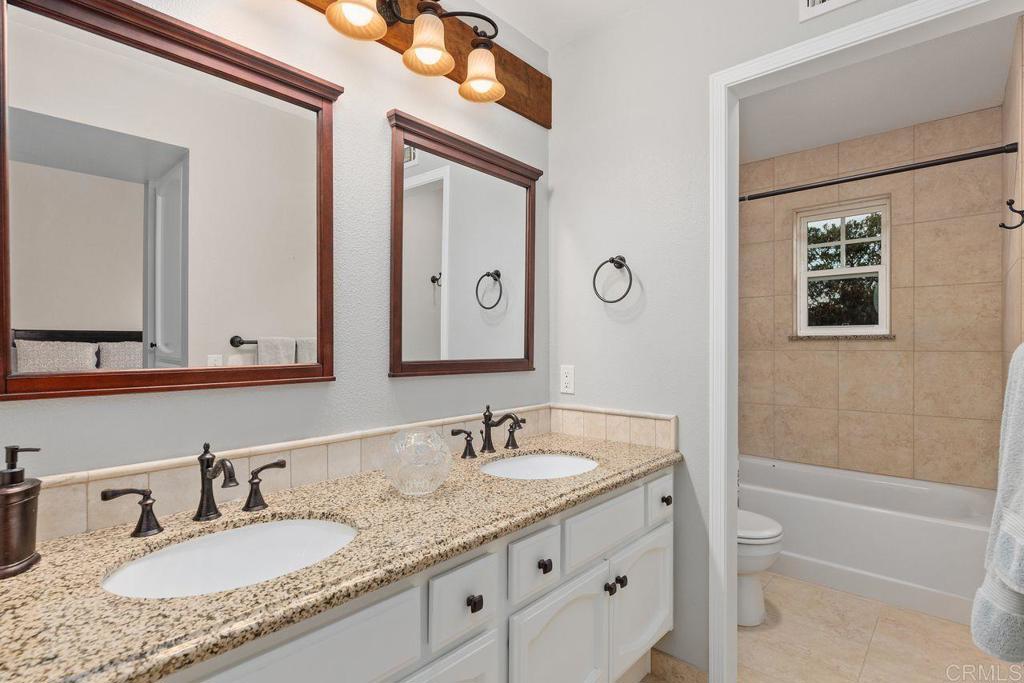 7325 Lantana Terrace Carlsbad, CA 92011 - Photo 23 of 36 a bathroom with a granite countertop double vanity sink and a mirror