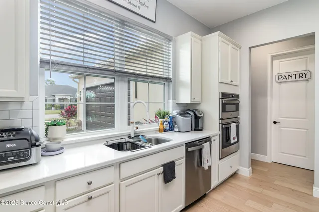 a kitchen with stainless steel appliances a sink a window and cabinets