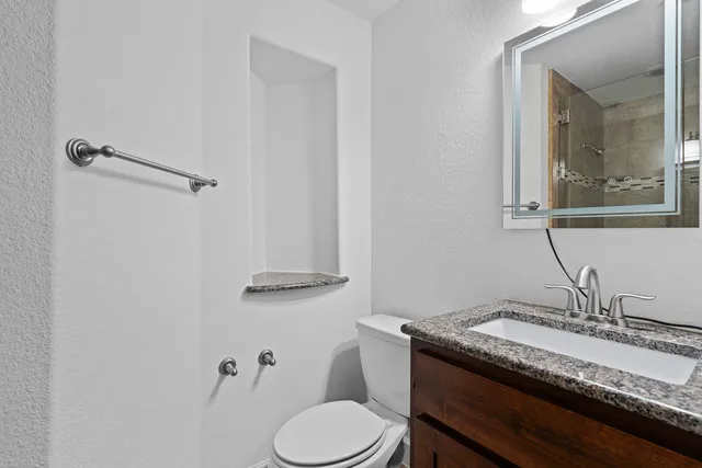 a bathroom with a granite countertop sink mirror and toilet