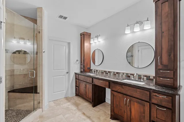 a bathroom with a double vanity sink mirror and shower
