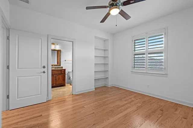 a view of empty room with wooden floor and ceiling fan