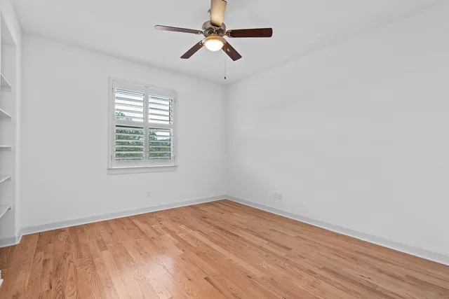 an empty room with a window and a ceiling fan