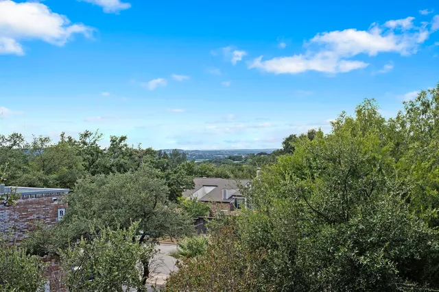 a view of a house with a small yard and a large tree