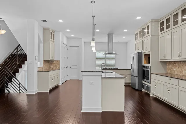 a kitchen with stainless steel appliances kitchen island wooden floors wooden cabinets and white appliances