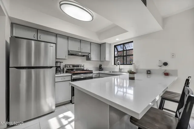 a kitchen with stainless steel appliances granite countertop a refrigerator a stove a sink a dining table and chairs