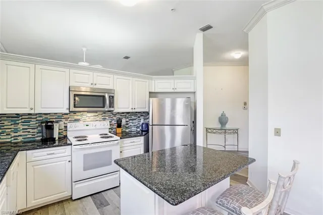 a kitchen with stainless steel appliances granite countertop a sink a stove a refrigerator cabinets and a dining table