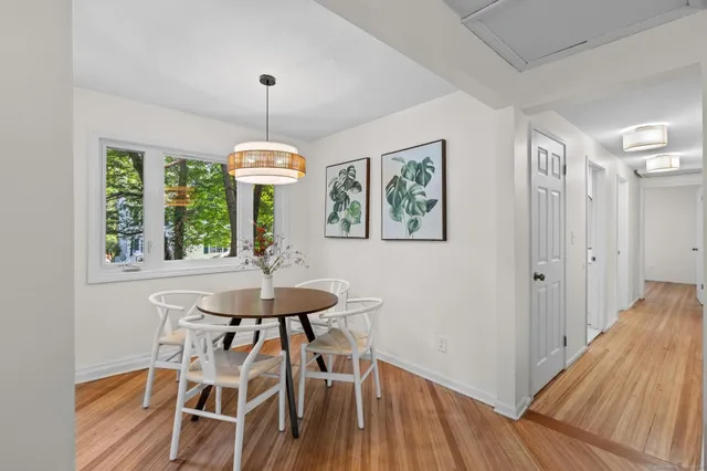 a dining room with wooden floor a chandelier a wooden table and chairs