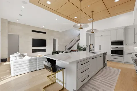 a large white kitchen with a large window a sink and stainless steel appliances