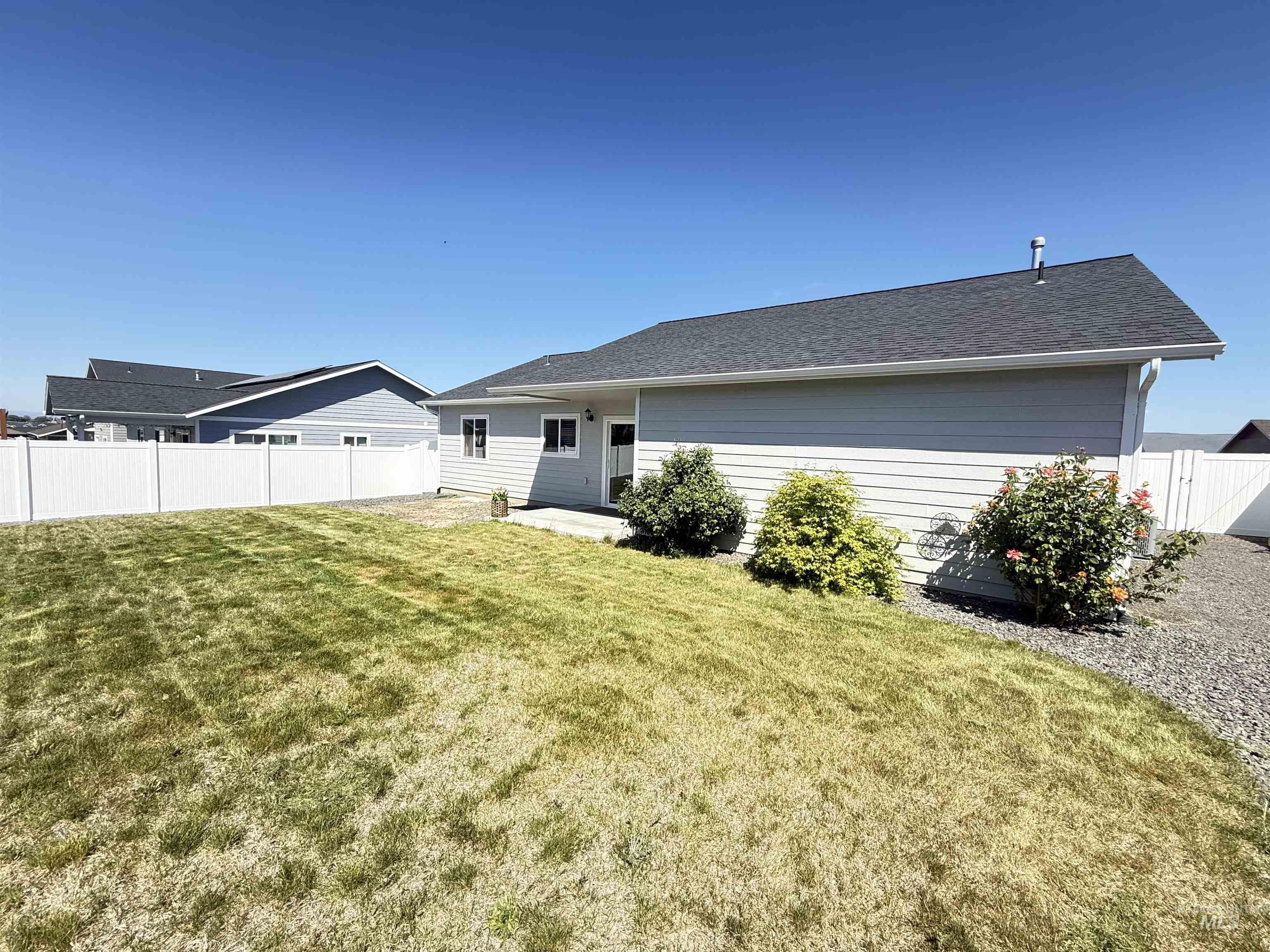 1556 Frontier Drive Lewiston, ID 83501 - Photo 19 of 23 Expansive side yard featuring a white vinyl fence, gravel landscaping, and mature shrubs