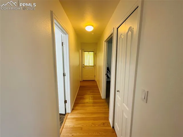 a view of a hallway with wooden floor and a bathroom