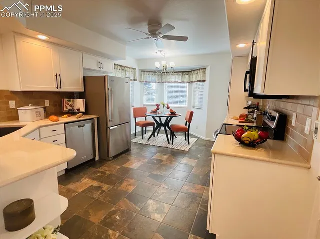 a kitchen with refrigerator and chairs