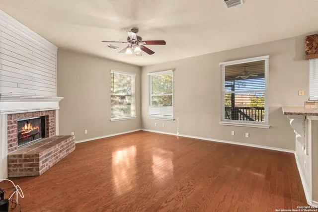 a view of an empty room with window and wooden floor
