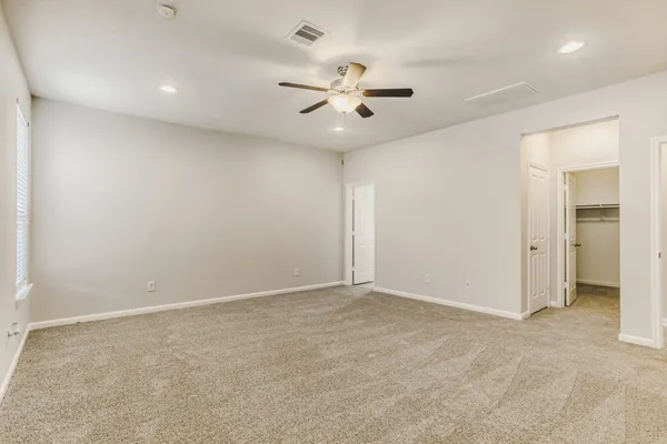 an empty room with closet and a ceiling fan