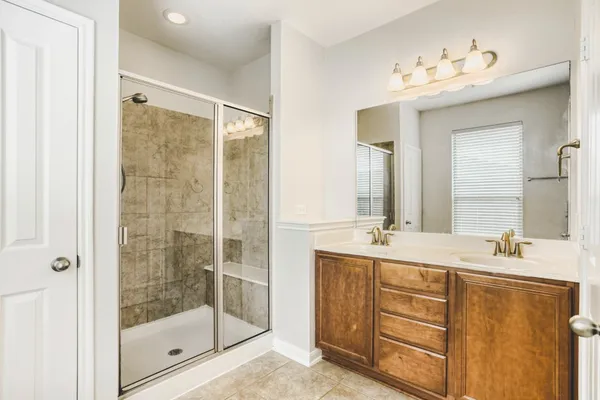 a bathroom with a double vanity sink mirror and shower
