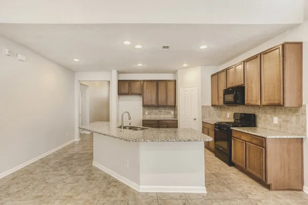 a large kitchen with stainless steel appliances granite countertop a stove a sink and a microwave