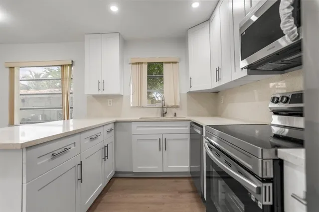 a kitchen with cabinets appliances a sink and a window