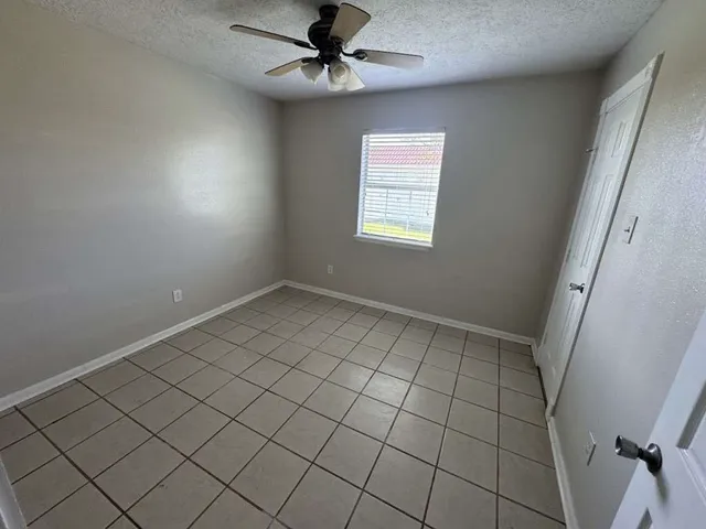 an empty room with windows and fan