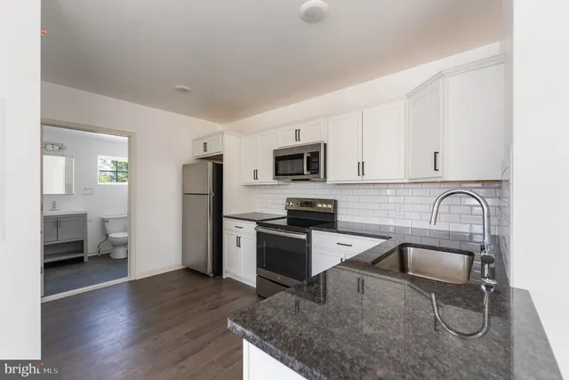 a kitchen with stainless steel appliances granite countertop a sink stove microwave and refrigerator