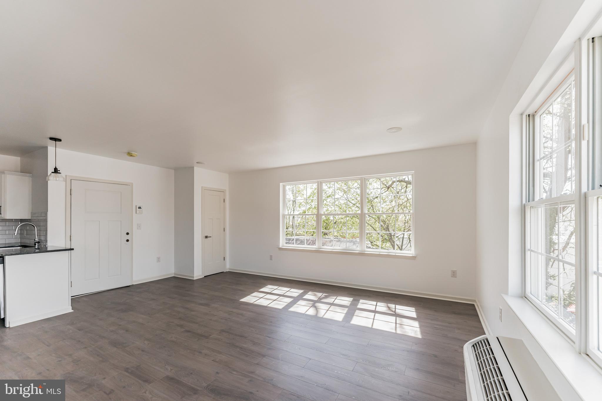 7105 Ridge Avenue, Unit B1 Philadelphia, PA 19128 - Photo 7 of 10 a view of an empty room with wooden floor and a window