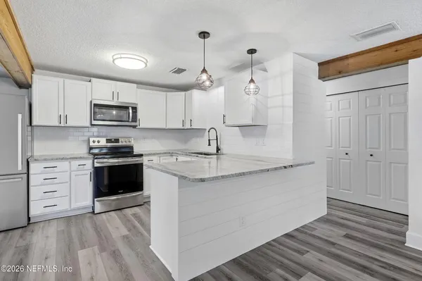 a kitchen with a sink dishwasher and white cabinets with wooden floor
