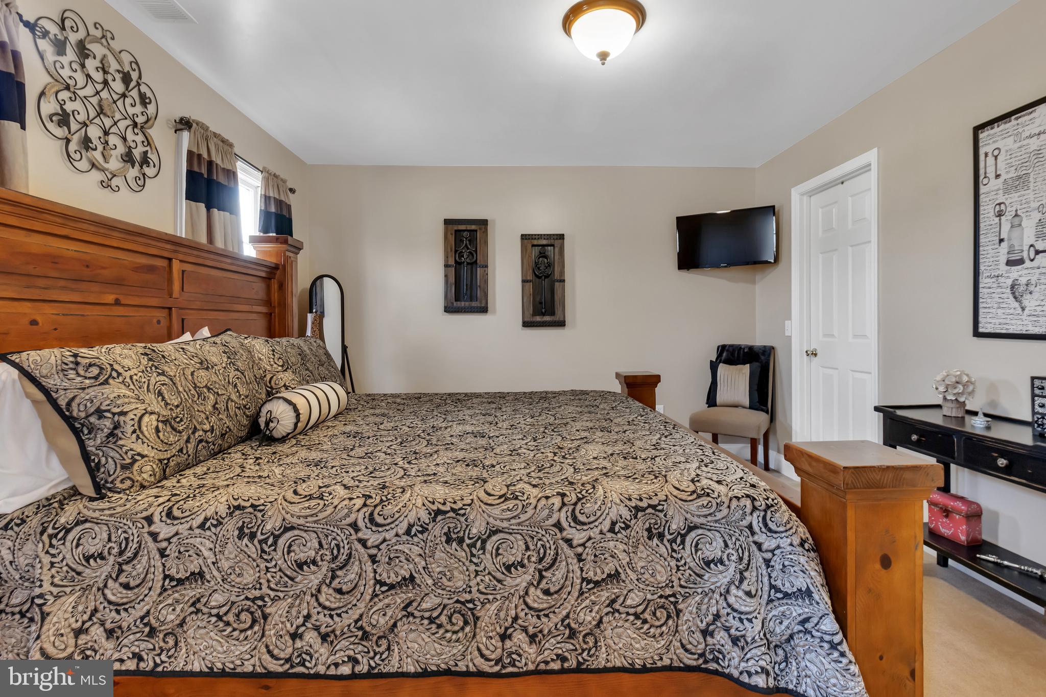 383 Connelly Road Rising Sun, MD 21911 - Photo 54 of 118 a bedroom with a bed a couch and a flat tv screen on the dresser