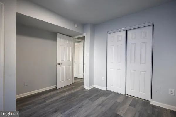 a view of an empty room and wooden floor & closet area