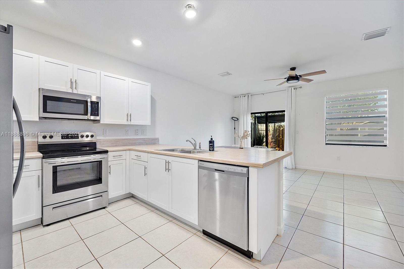 10013 Southwest 228th Terrace, Unit 10013 Miami, FL 33190 - Photo 13 of 39 a kitchen with stainless steel appliances a stove sink and microwave