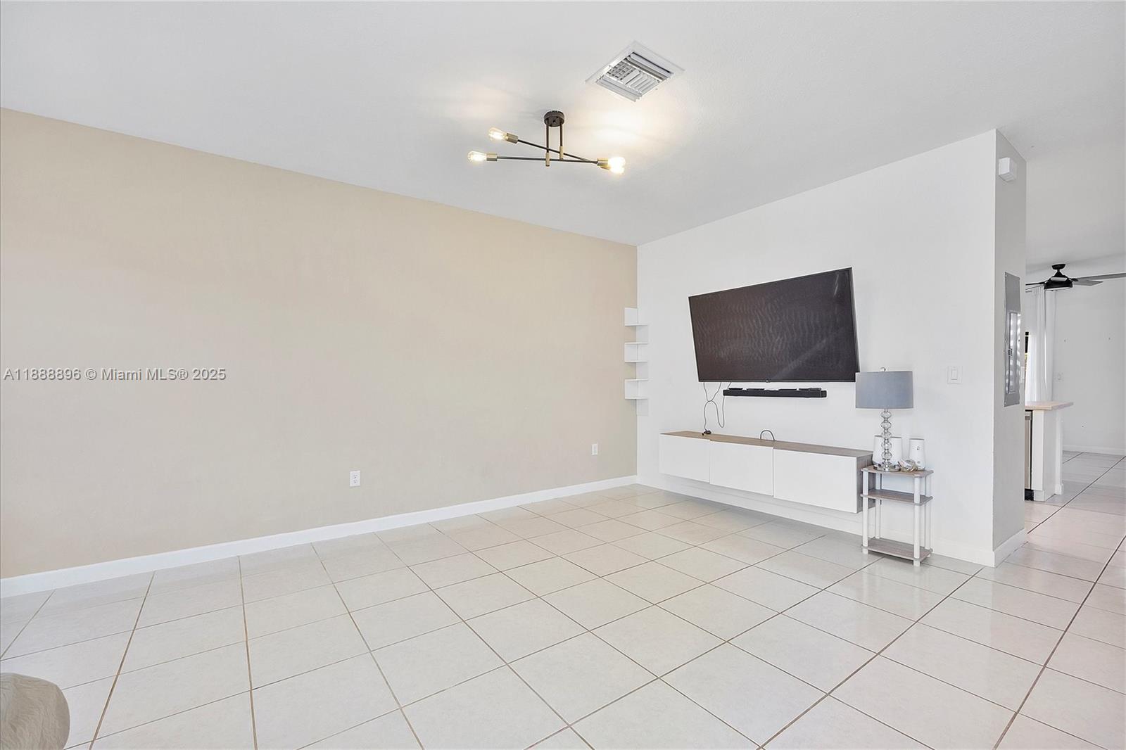 10013 Southwest 228th Terrace, Unit 10013 Miami, FL 33190 - Photo 2 of 39 a view of an empty room with a tv and wooden floor
