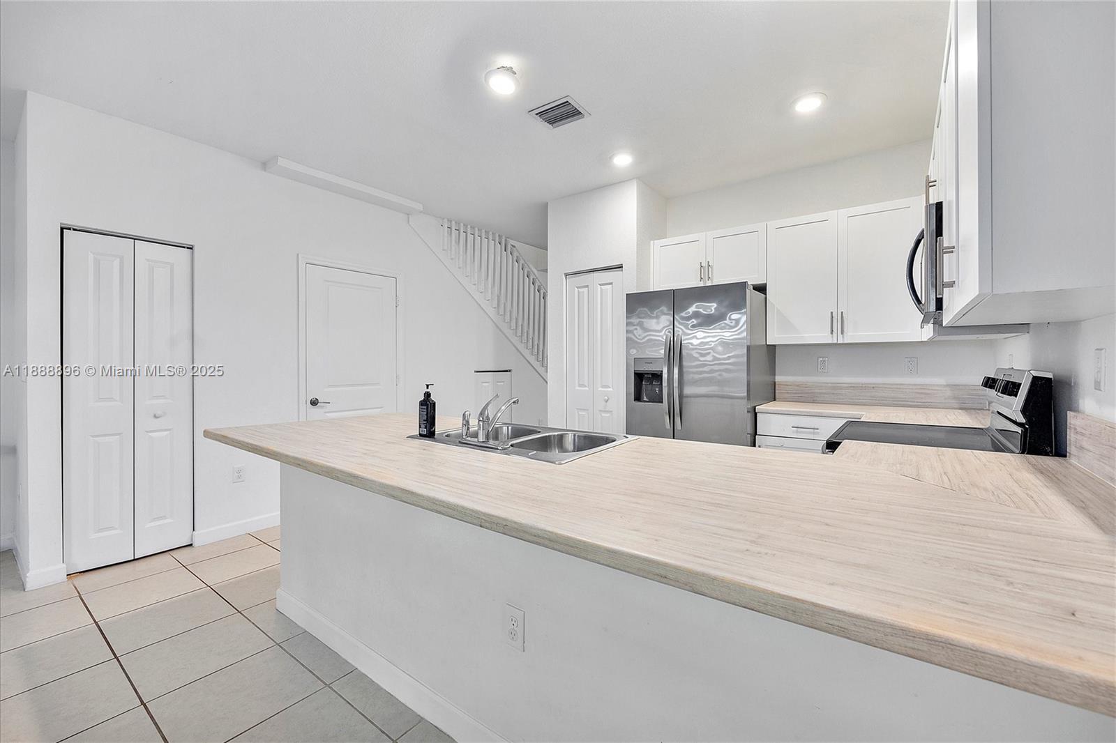 10013 Southwest 228th Terrace, Unit 10013 Miami, FL 33190 - Photo 8 of 39 a large white kitchen with kitchen island a sink stainless steel appliances and cabinets