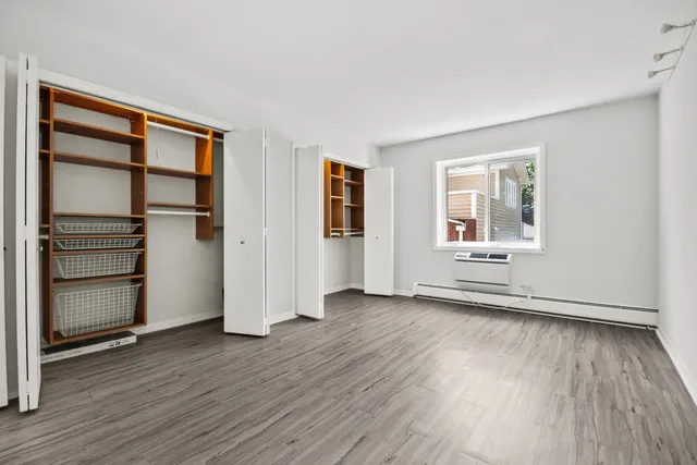 an empty room with wooden floor closet and windows
