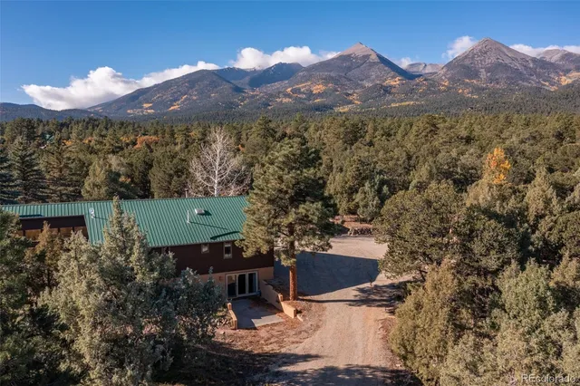 a view of a house with a yard and mountain view in back