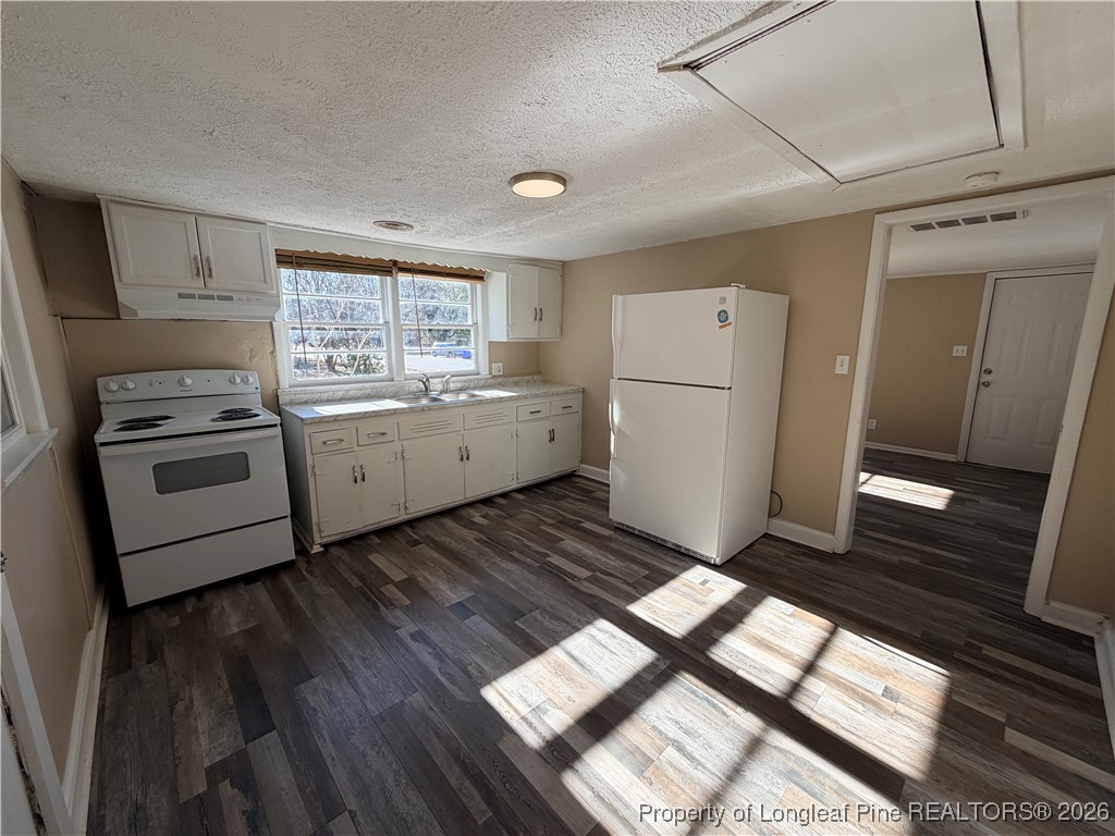 1925 Progress Street Fayetteville, NC 28306 - Photo 8 of 12 a kitchen with a stove a refrigerator and white cabinets