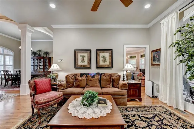 a living room with lots of furniture kitchen view and a chandelier